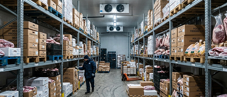 Operator working in a cold storage warehouse with meat products under strict hygiene and temperature controls