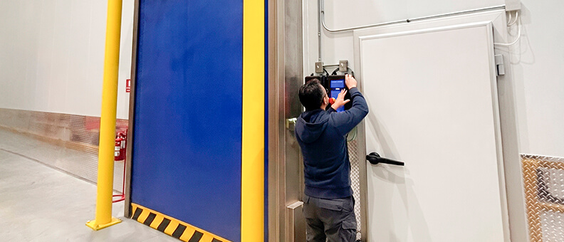 Technicien spécialisé contrôlant et testant l'armoire de commande d'une porte industrielle